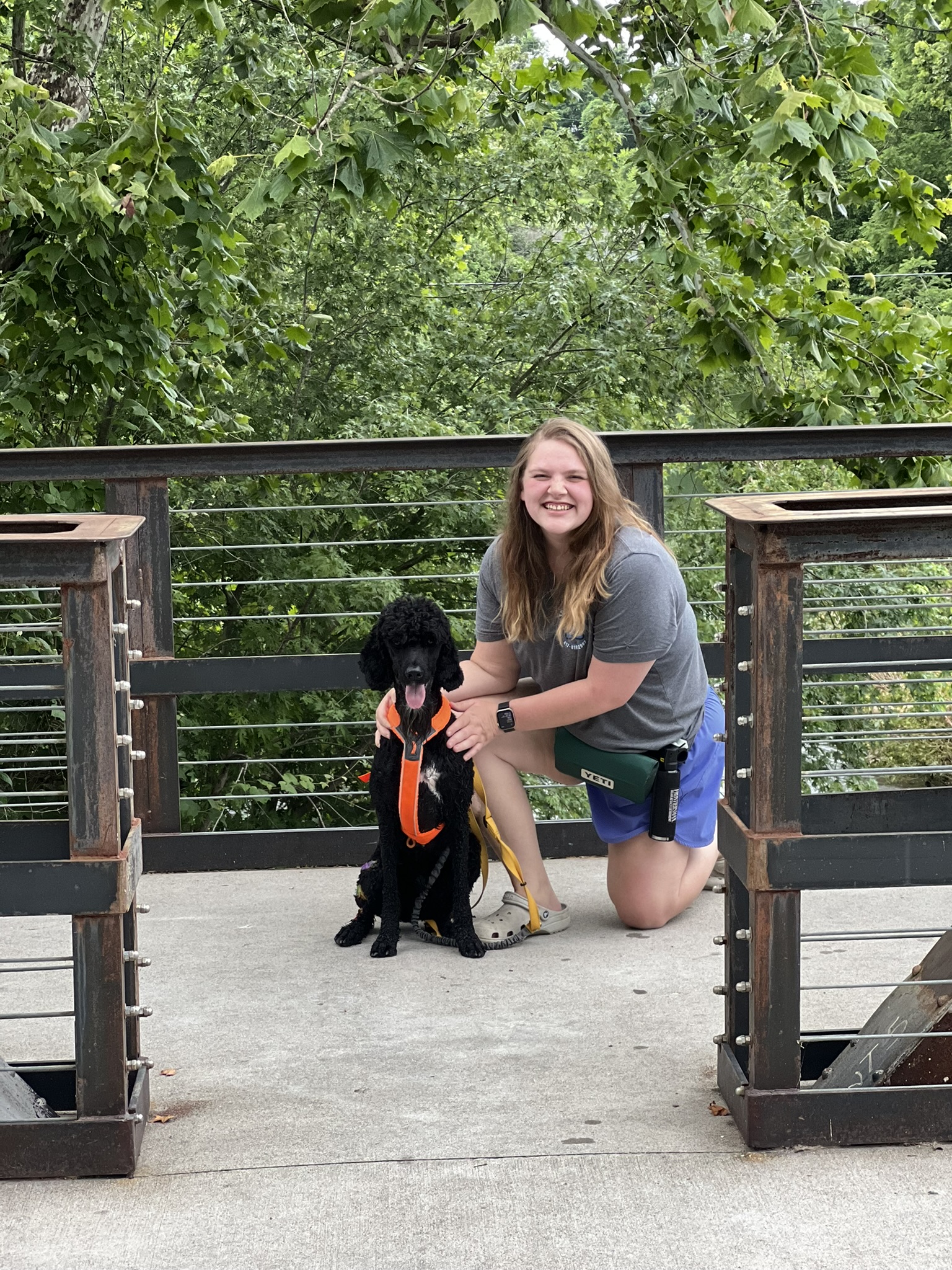 Mahlorie kneeling beside Bo outdoors on a bridge